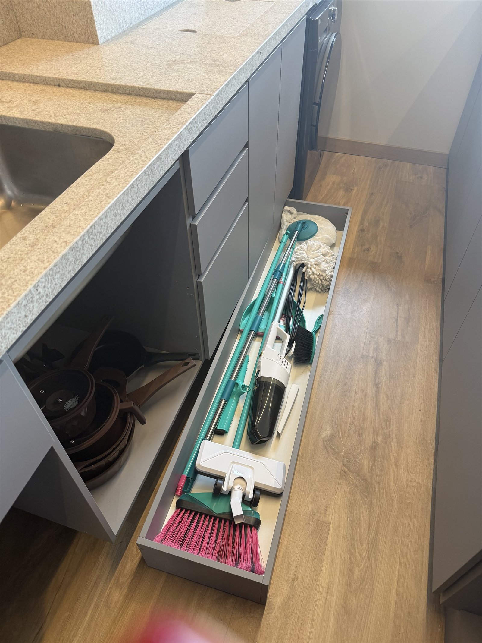 Gaveta organizadora com utensílios de limpeza, aspirador e vassouras
