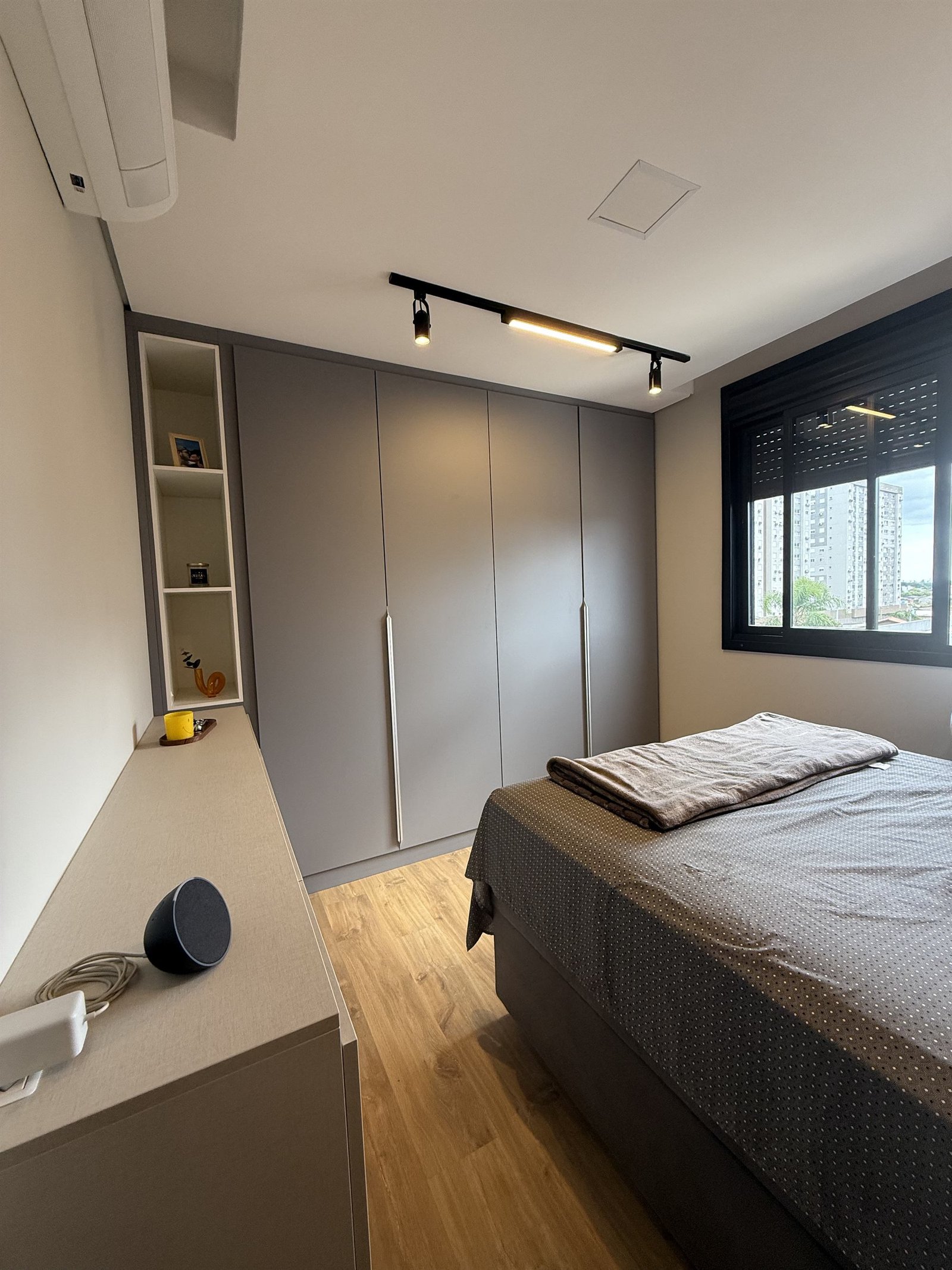 Quarto do casal, com guarda-roupa cinza do chão ao teto e iluminação em trilho