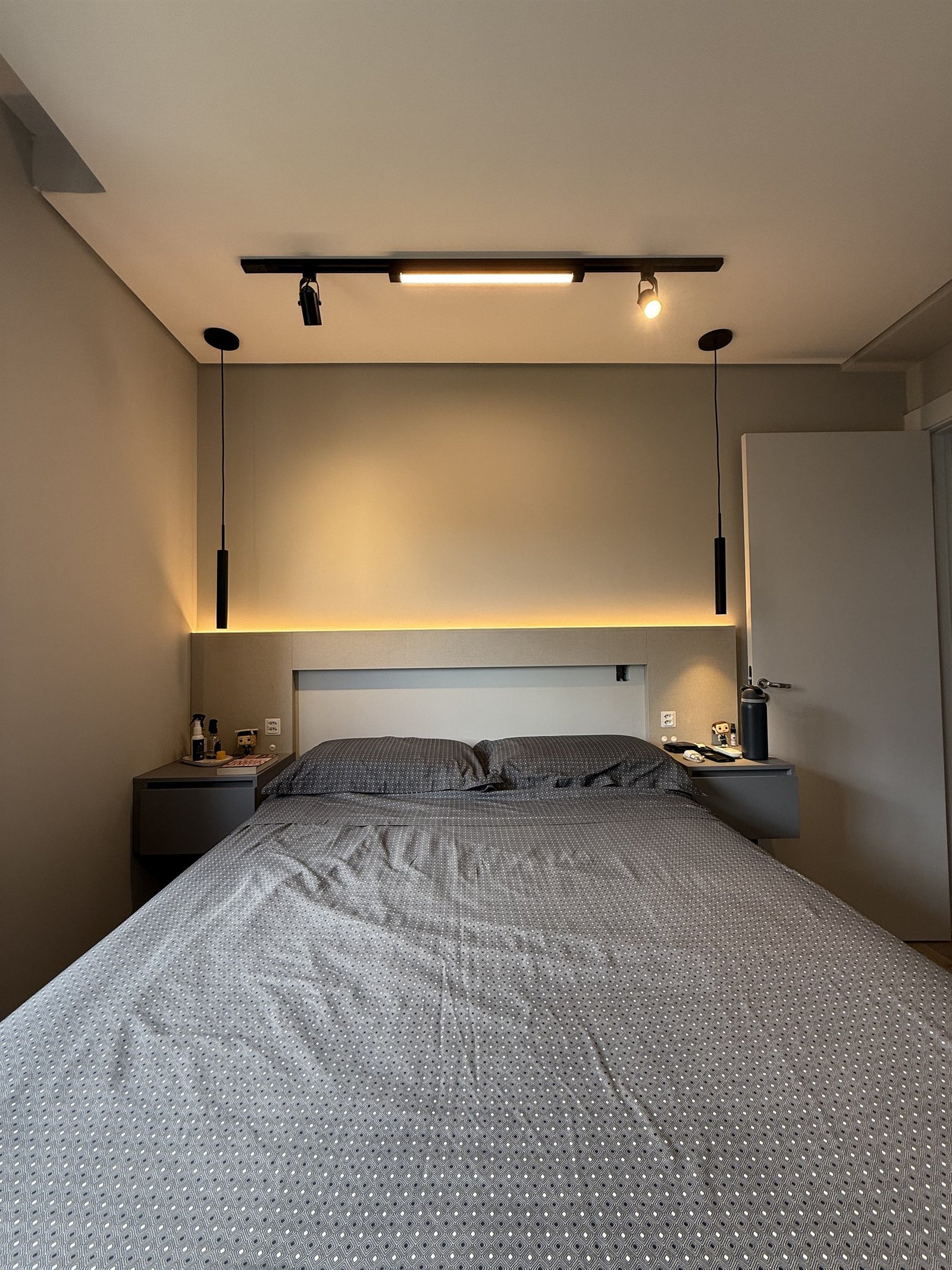 Cabeceira do quarto com luz indireta e pendentes pretos