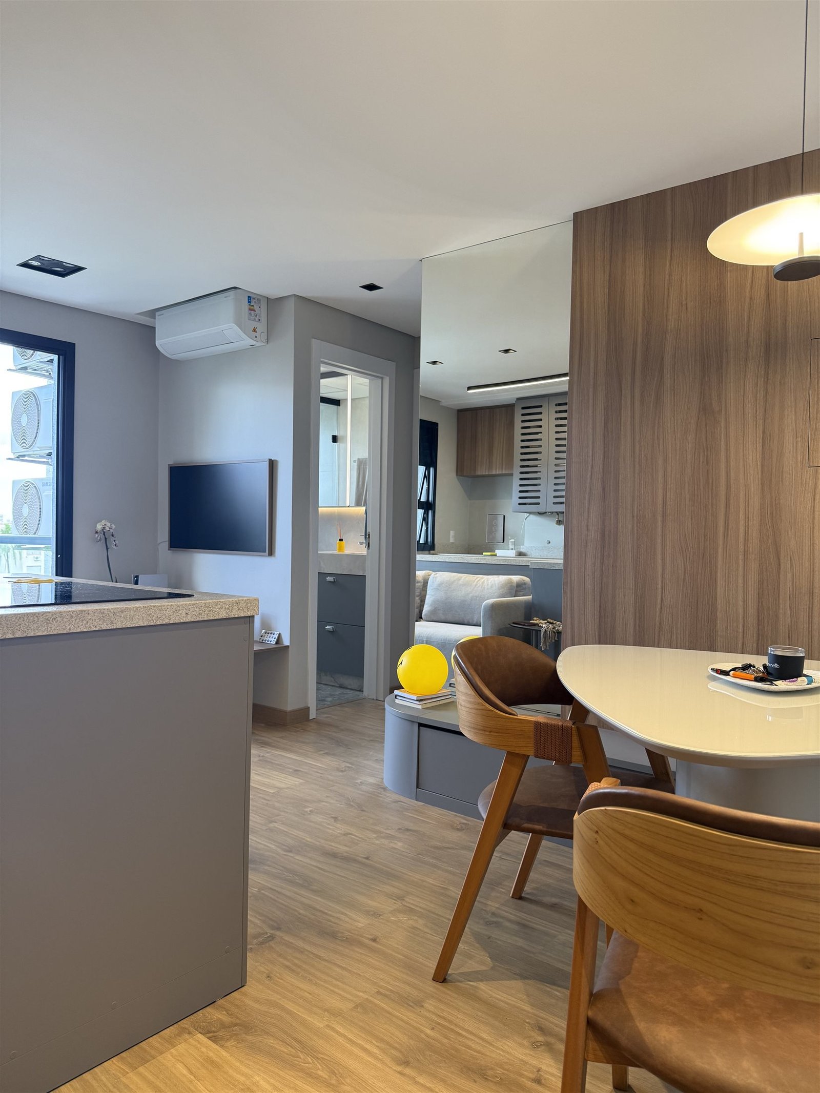 Sala e cozinha integradas, vista ampla com a porta do banheiro ao fundo