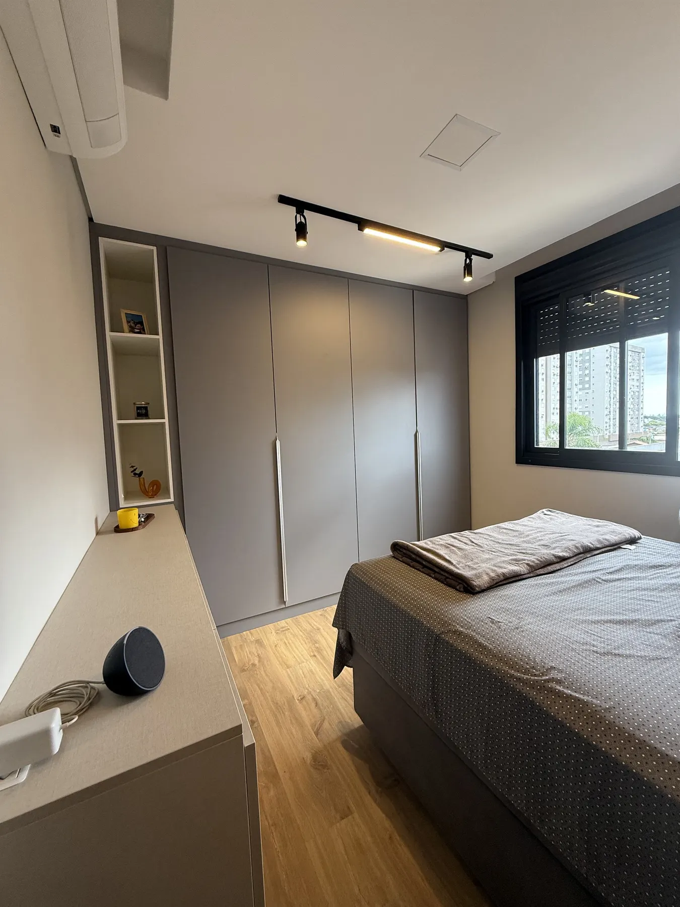 Quarto do casal, com guarda-roupa cinza do chão ao teto e iluminação em trilho