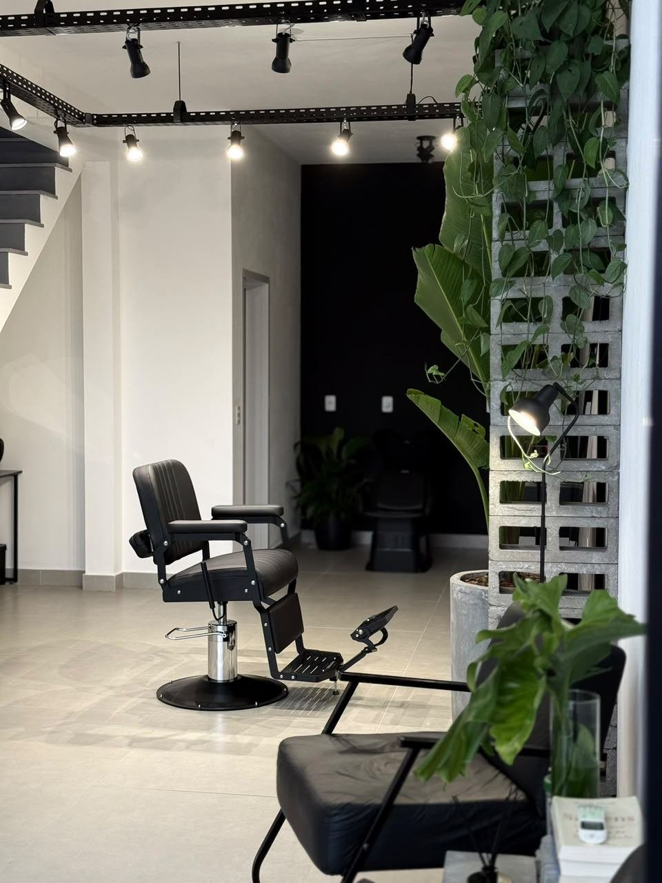 Térreo pronto, com poltrona de barbeiro, escada e pilar de blocos de cimento com plantas