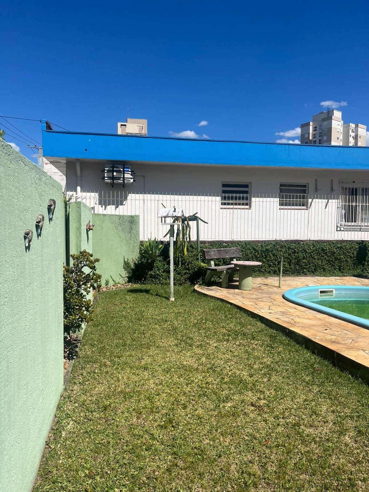 Vista ampla do quintal antigo antes da reforma, com muro verde e telhado azul