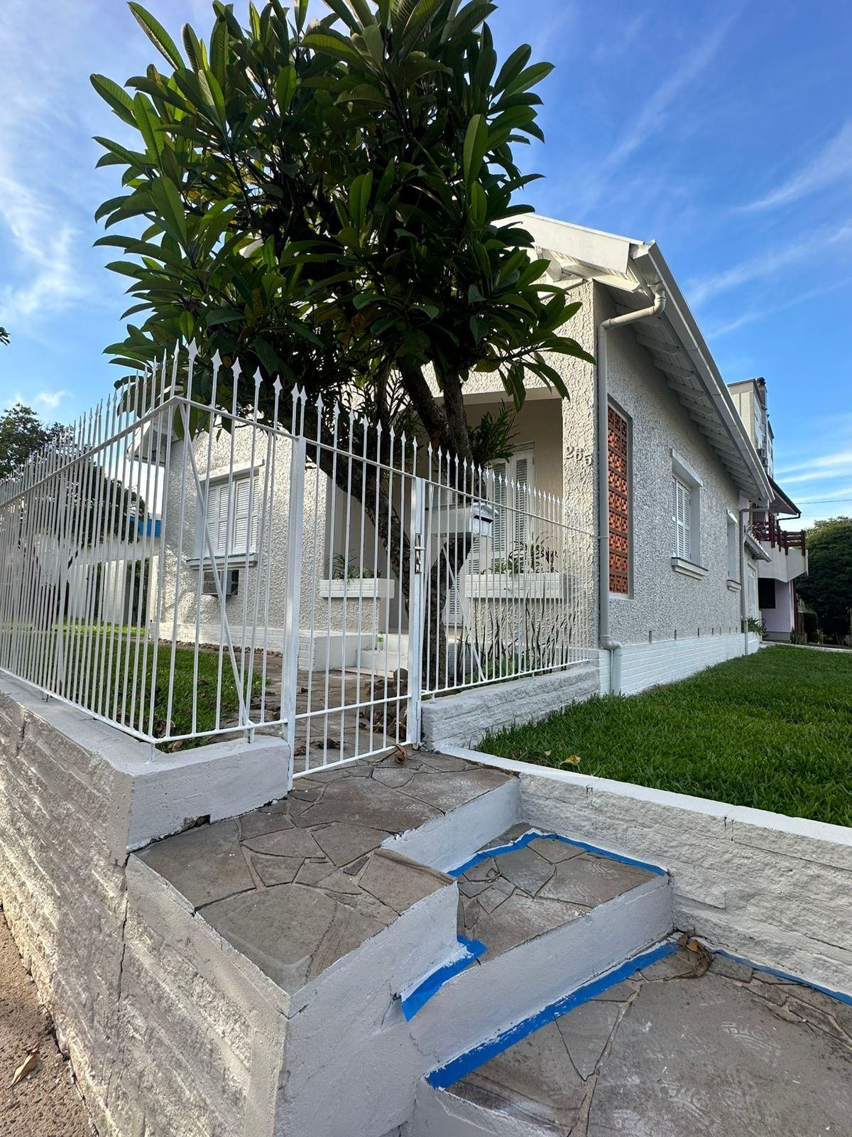 Fachada frontal da casa vista da rua, já repintada, com o número na parede