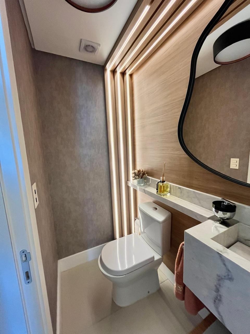 O mesmo lavabo pronto, com o painel ripado e a iluminação linear acesa