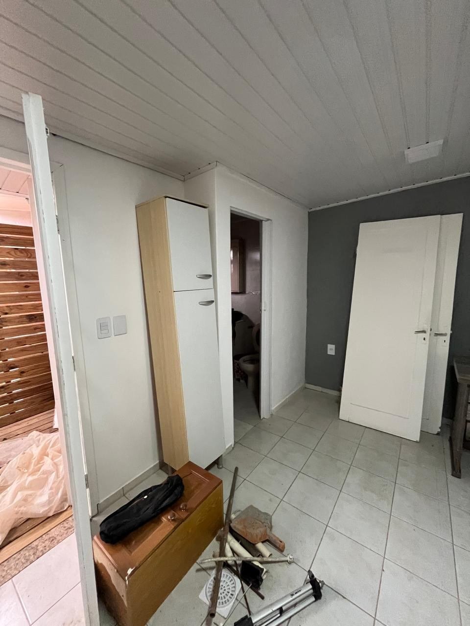 Canto da sala antes da reforma, com móveis antigos e obra em andamento