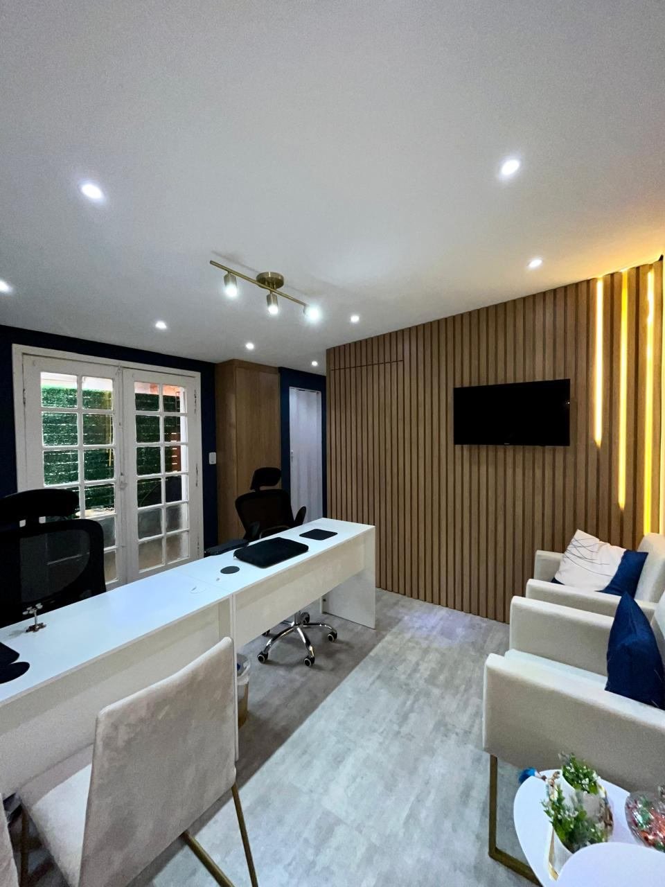 Divisória em marcenaria ripada com TV embutida e iluminação em LED, separando o DG Studio do escritório de advocacia