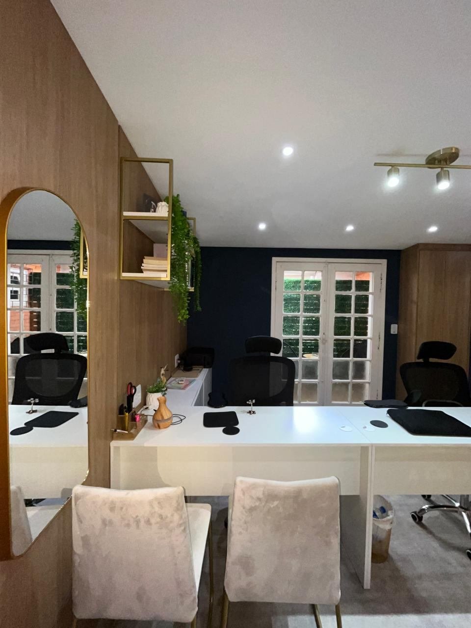 Studio da Débora do outro lado da marcenaria, com espelho arqueado, mesa e cadeiras de atendimento